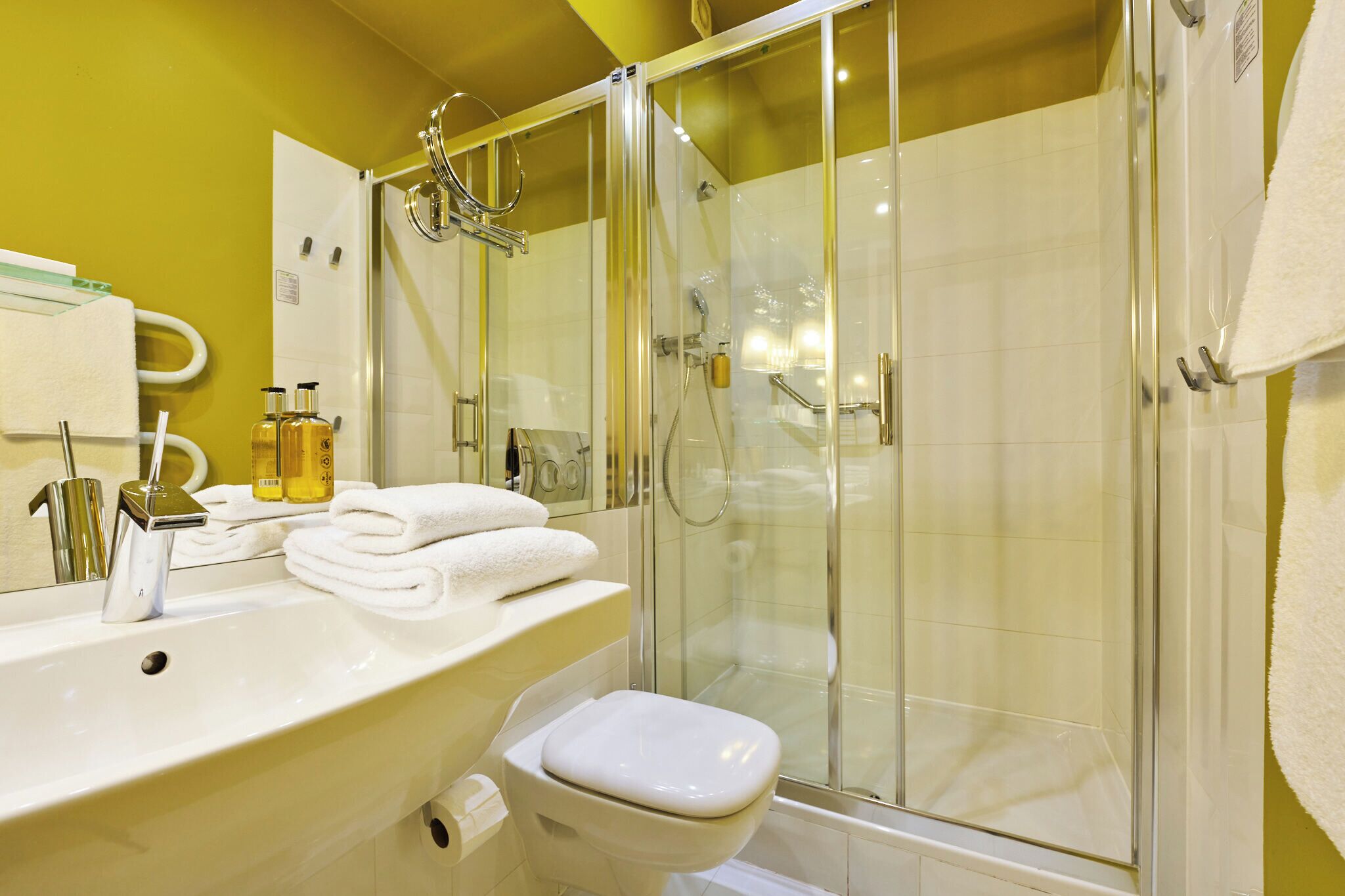 Un baño con lavamanos, inodoro y ducha con mampara de vidrio.