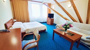 A hotel room with two beds, a sofa, a desk, a TV, and a window with curtains. - Panorama Hotel - Downtown (Szczecin)