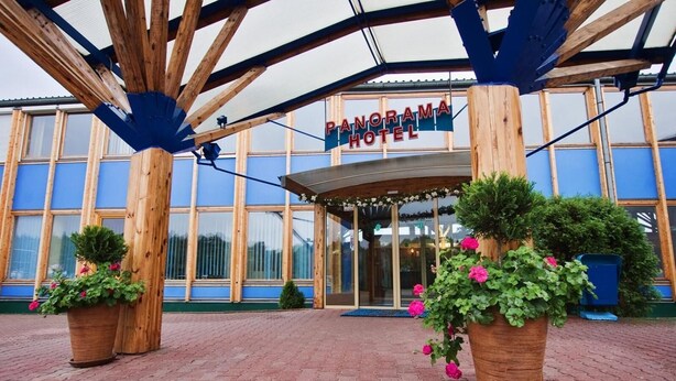 A hotel entrance with a covered walkway, large windows, and potted plants. - Panorama Hotel - Downtown (Szczecin)