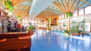 A spacious lobby with a blue floor, wooden ceiling beams, and potted plants. - Panorama Hotel - Downtown (Szczecin)
