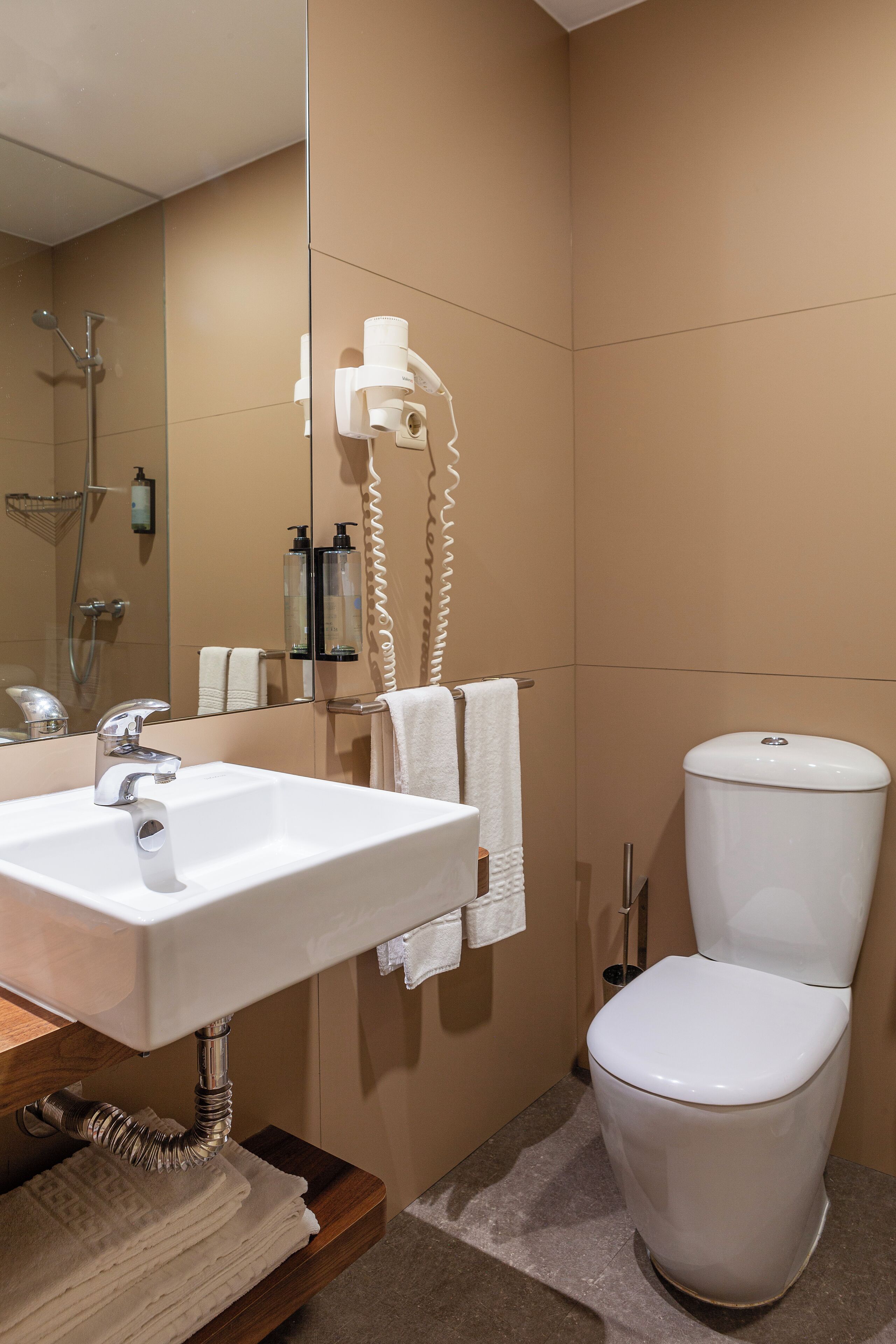 A bathroom with a sink, mirror, towel rack, toilet, and shower.
