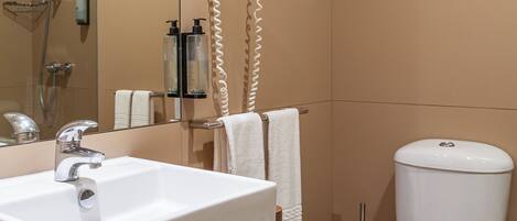 A bathroom with a sink, mirror, towel rack, toilet, and shower.