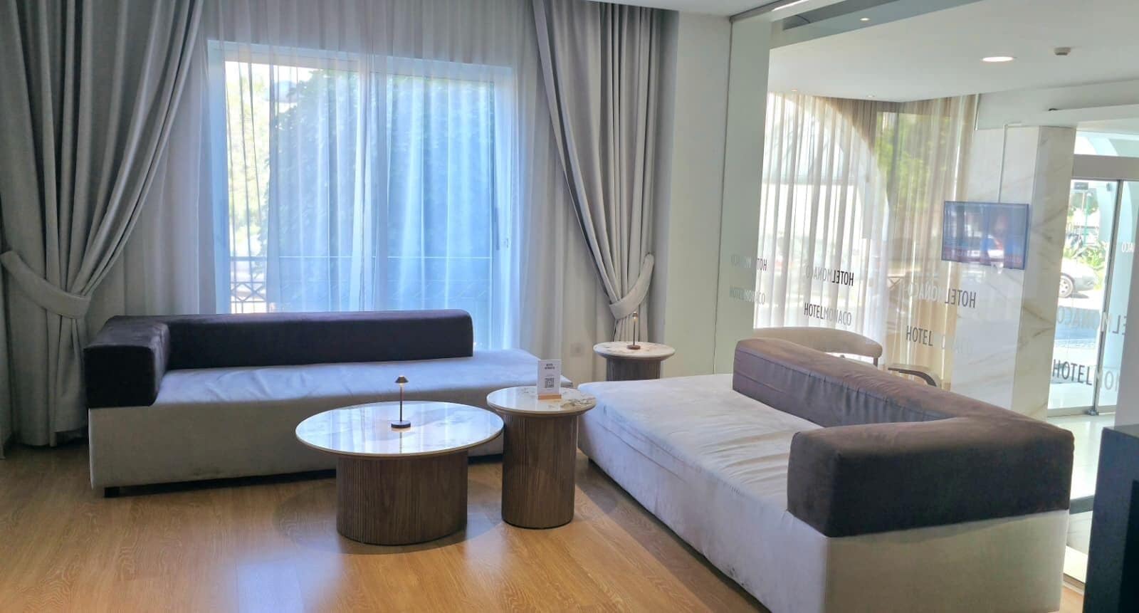 A modern hotel room with a sofa, two side tables, and a television.