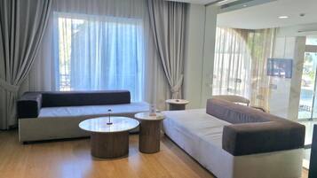 A modern hotel room with a sofa, two side tables, and a television.