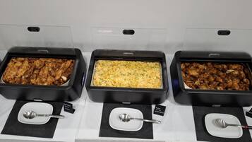 Buffet com três bandejas de comida, cada uma identificada com um prato diferente.