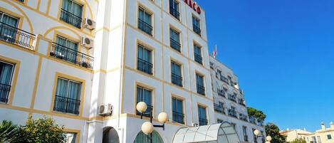 A multi-story hotel with a prominent 'HOTEL MONACO' sign, large windows, and a covered entrance.