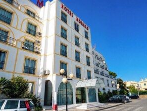A multi-story hotel with a prominent 'HOTEL MONACO' sign, large windows, and a covered entrance.