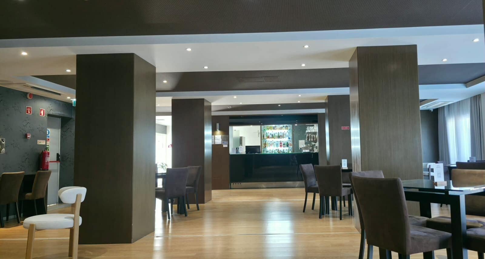 Un interior moderno con una zona de bar, asientos y un extintor visible.
