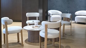 A modern hotel lobby with a seating area featuring round tables and white chairs.