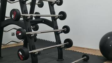 A gym with a squat rack, barbell, and dumbbells.