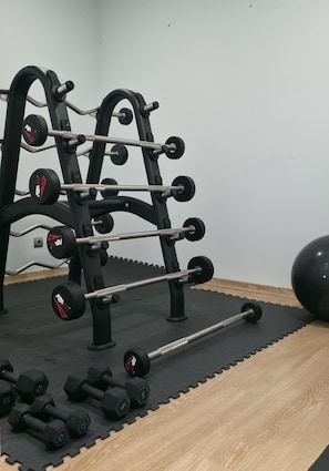 A gym with a squat rack, barbell, and dumbbells.