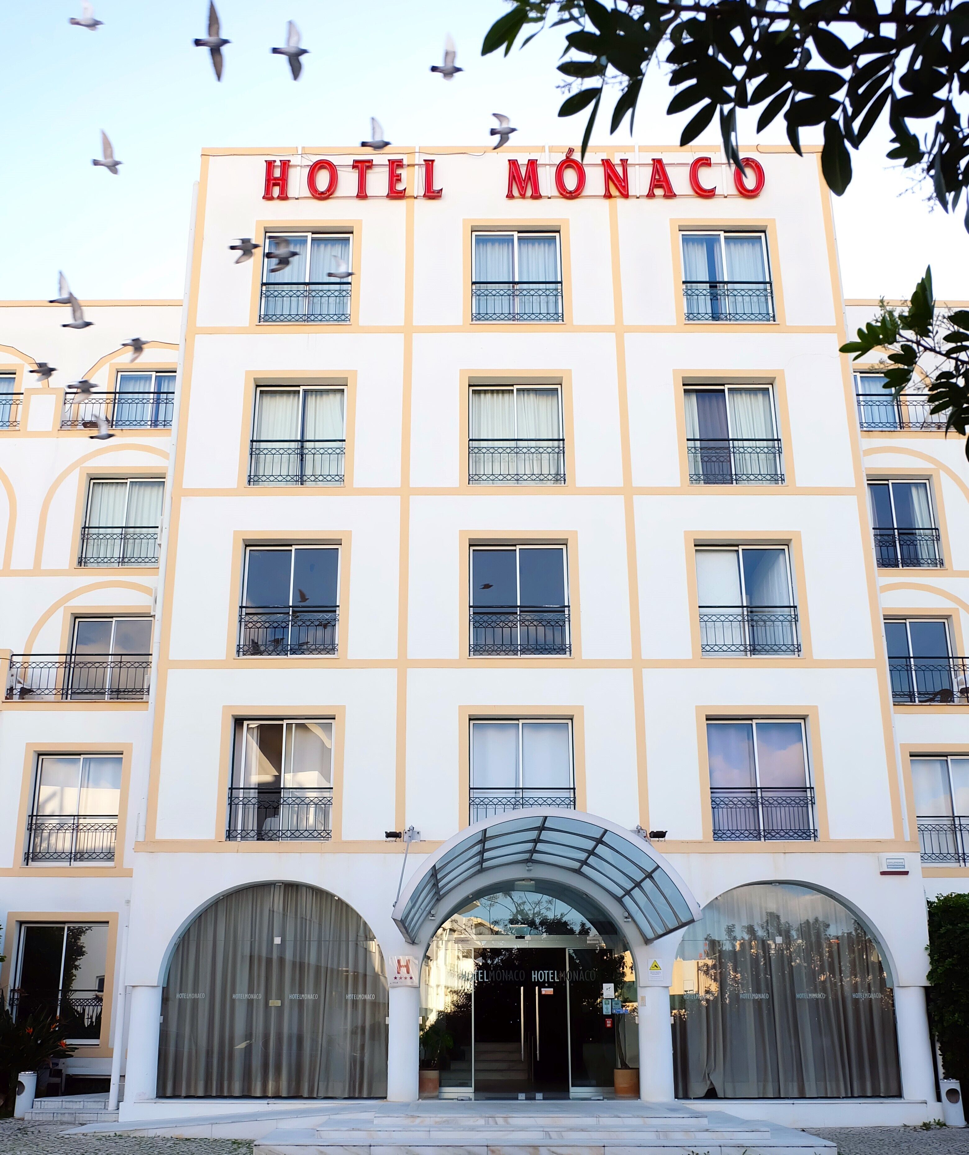 A hotel building with multiple balconies and a sign that reads 'HOTEL MONACO'.