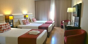 A hotel room with two beds, a TV, a desk, and a chair.