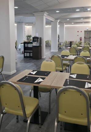 A dining area with yellow chairs and tables, a buffet station, and a conference room with chairs and tables.