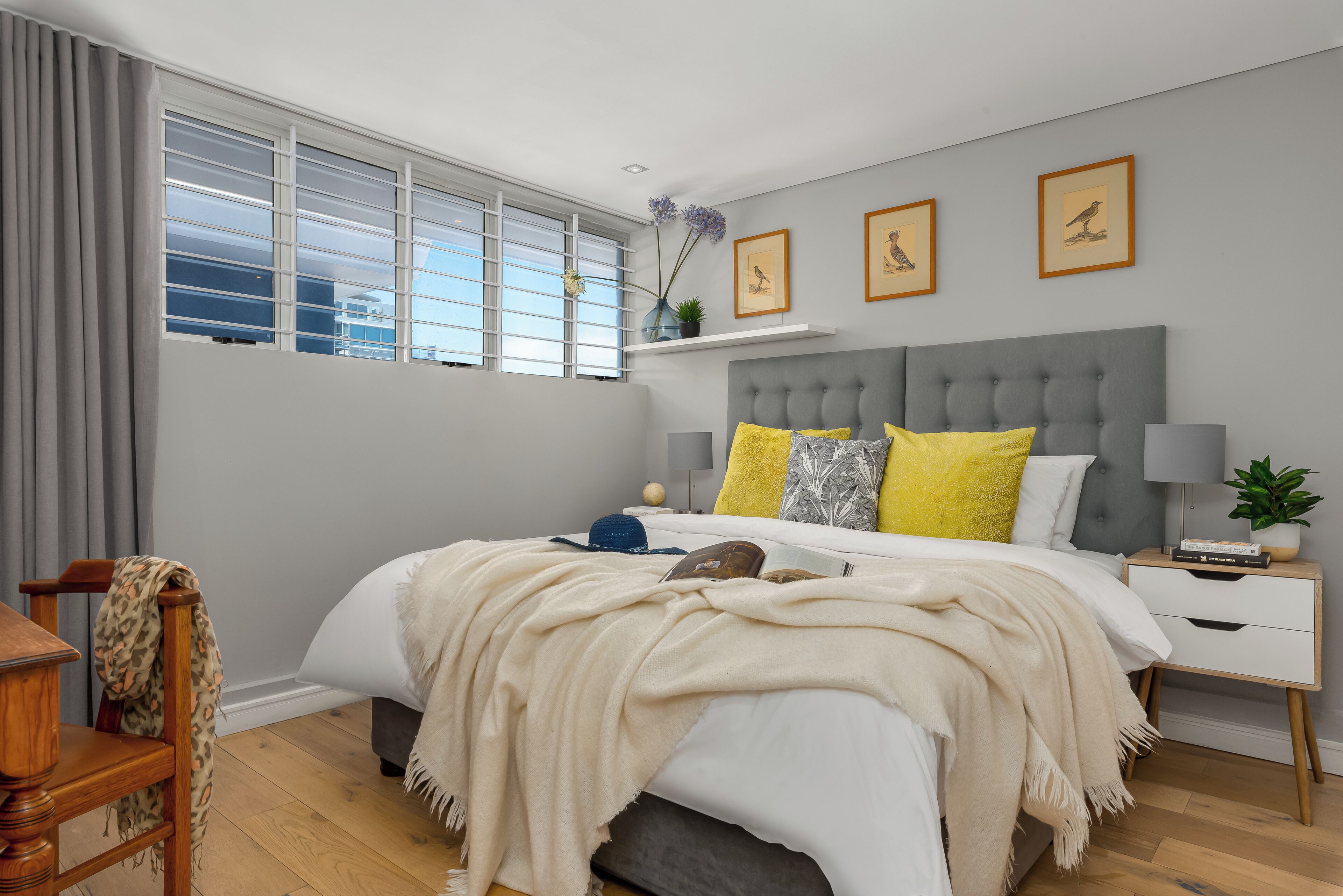 A bedroom with a bed, bedside tables, a nightstand, a chair, and a window with curtains.