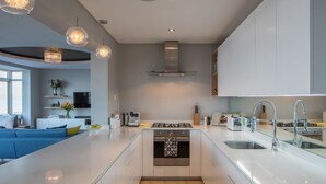 A modern kitchen with white cabinetry, a central island, stainless steel appliances, and pendant lighting. - 24 Villa Marina (Cape Town)