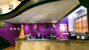A reception desk with three staff members, purple walls, and various sculptures. - Cape Town Lodge Hotel (Cape Town)