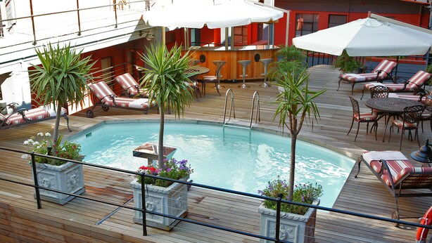 A pool area with lounge chairs and umbrellas on a wooden deck. - Cape Town Lodge Hotel (Cape Town)