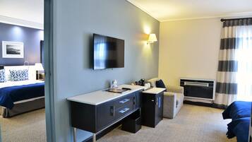 A hotel room with a bed, a desk, a television, and a window with curtains.
