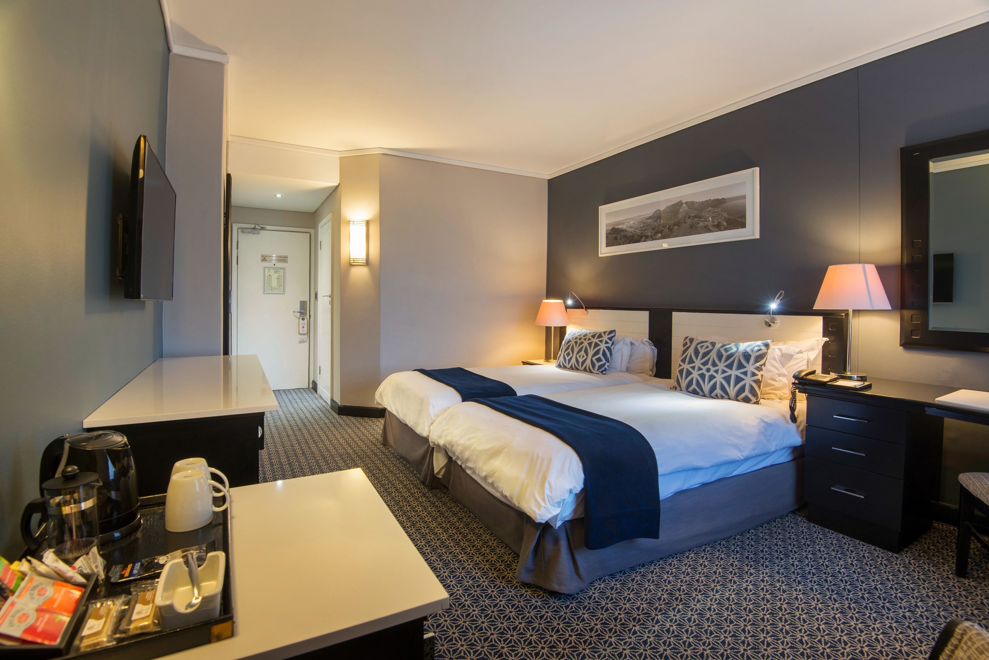 Une chambre d’hôtel équipée d’un lit, de tables de chevet, d’un bureau, d’une machine à café et d’un téléviseur.