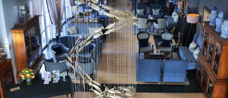 A spacious lobby with a large wooden floor, a central decorative sculpture, and a seating area with sofas and chairs.