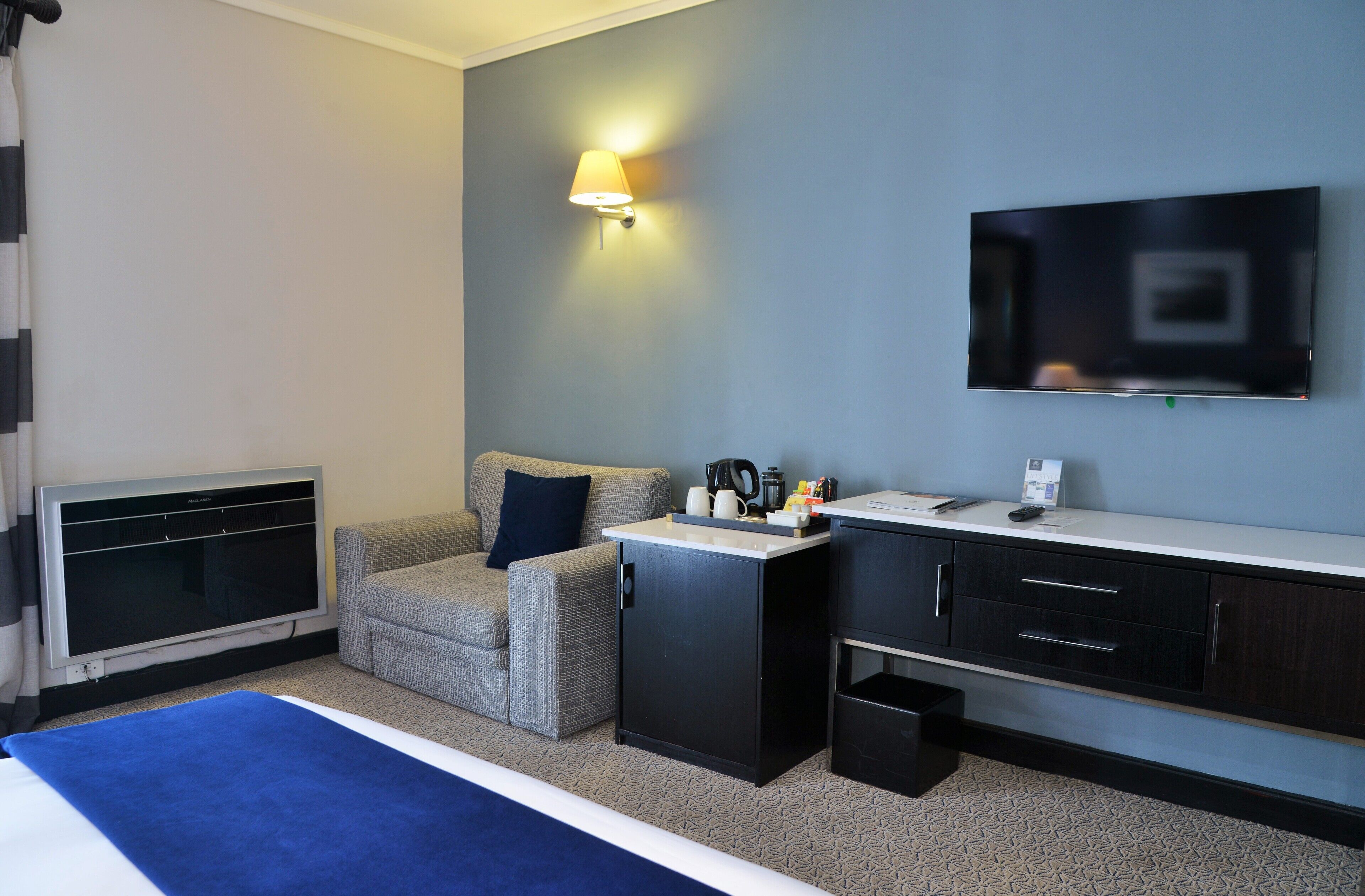 Ett hotellrum med en säng, ett skrivbord, en tv och ett litet pentry.