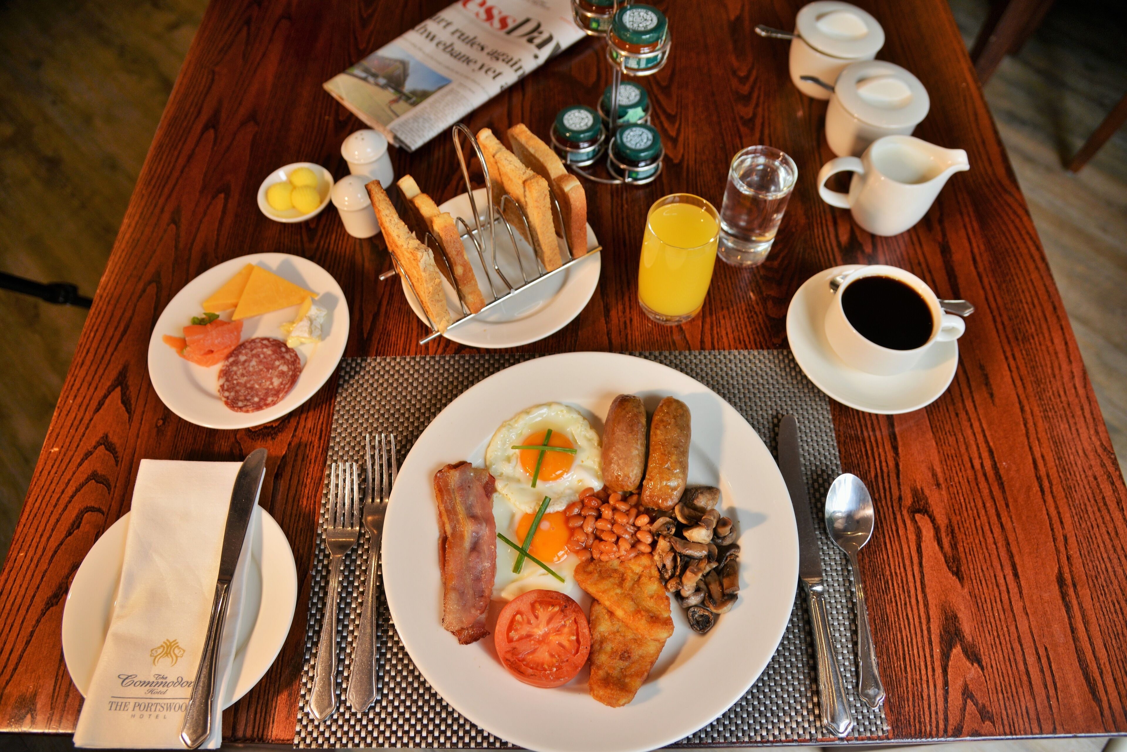 Una mesa de desayuno con platos de comida, cubiertos y aderezos.