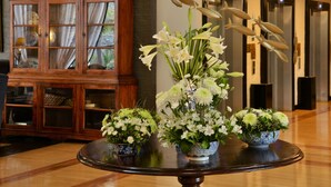 Un vestíbulo con un mueble de madera, una mesa redonda con arreglos florales y una escultura de pez colgante.