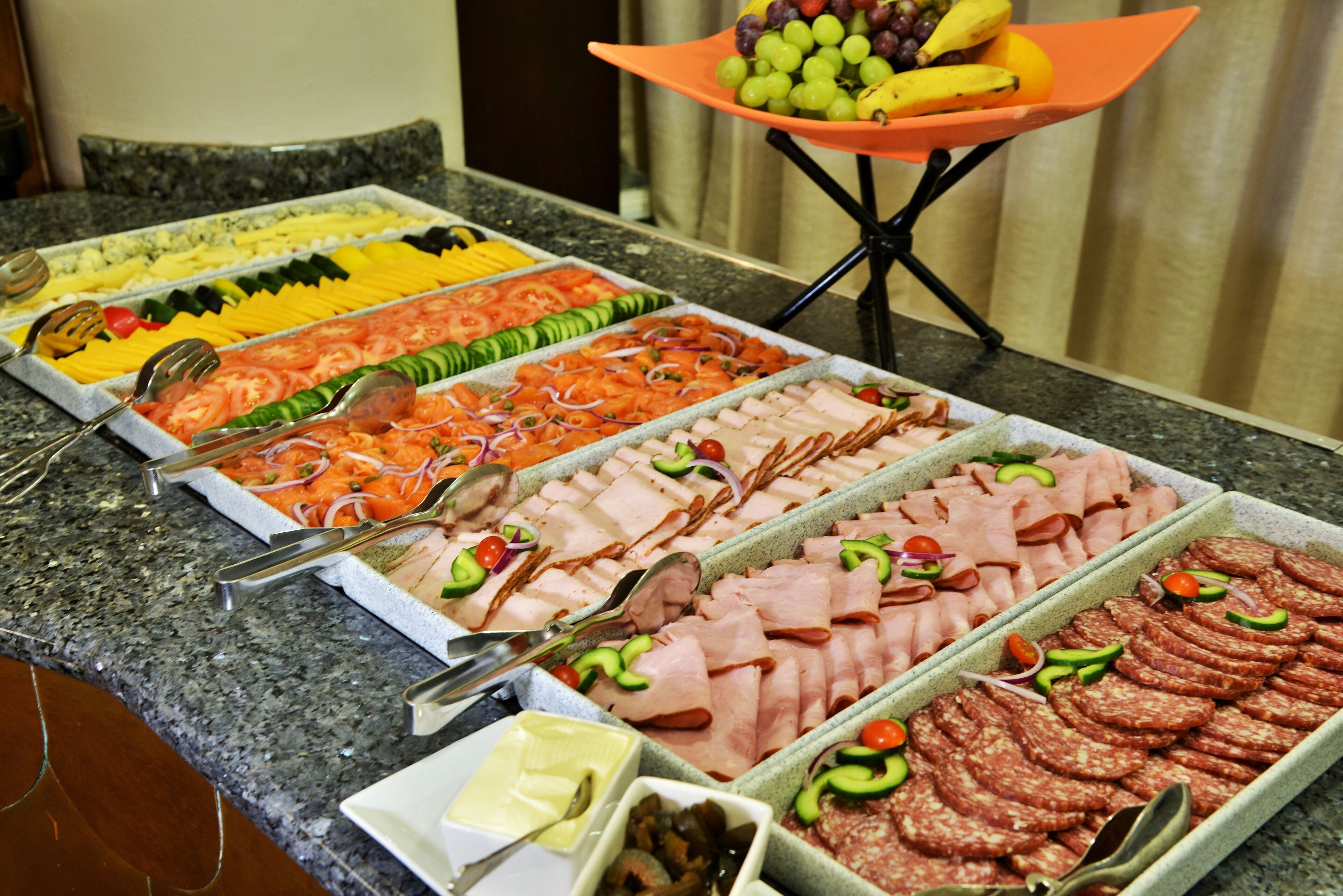 Un buffet proposant une variété de plats, notamment des viandes, des fromages et des fruits.