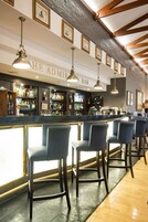 A bar area with a counter, bar stools, and framed pictures on the wall.