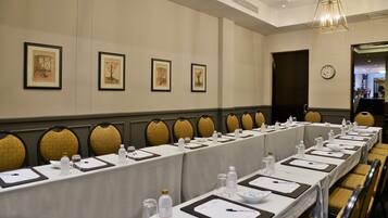 A conference room with long tables, chairs, and framed artwork on the wall.
