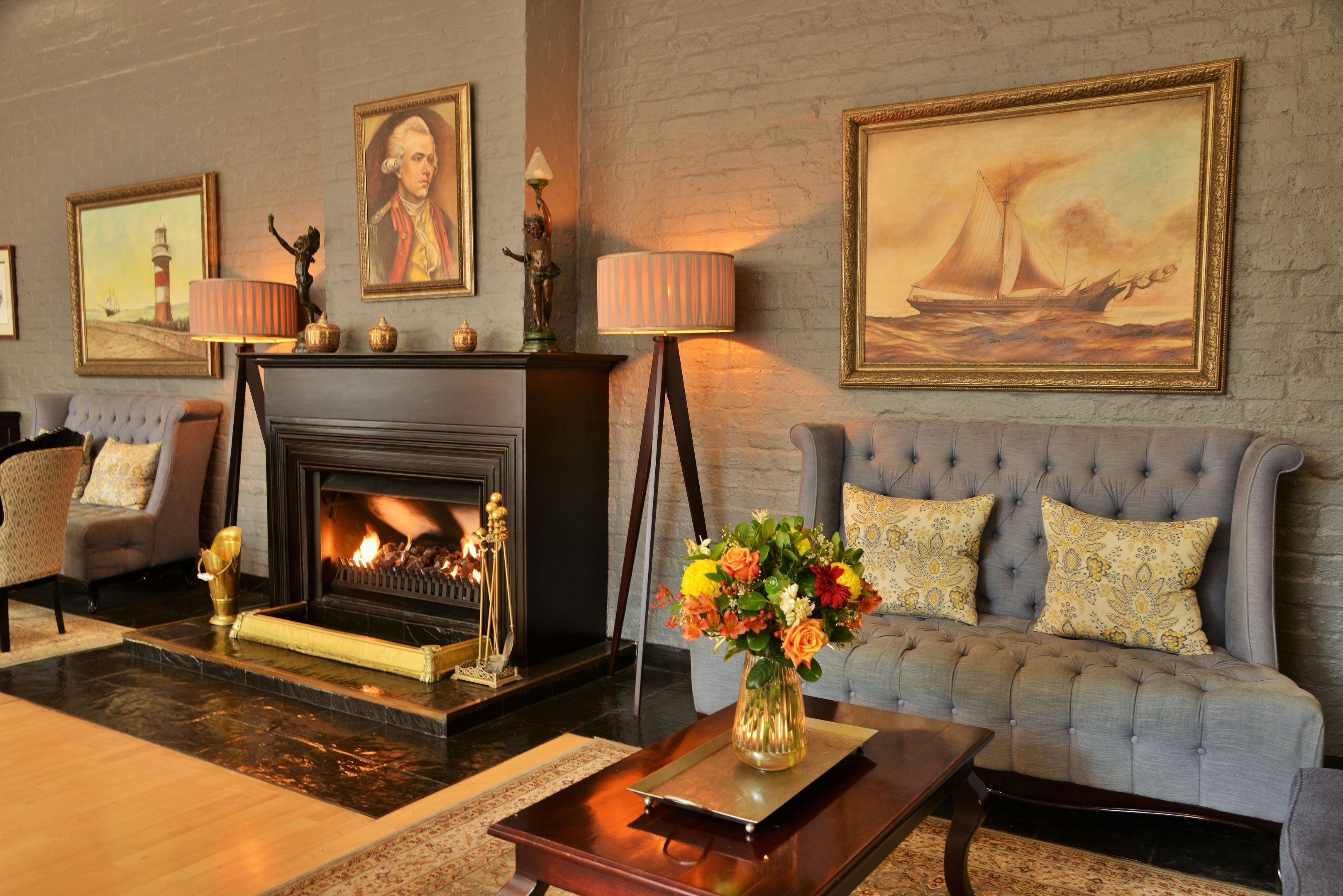 Una sala de estar con chimenea, un sofá, una mesita de centro y un jarrón con flores.