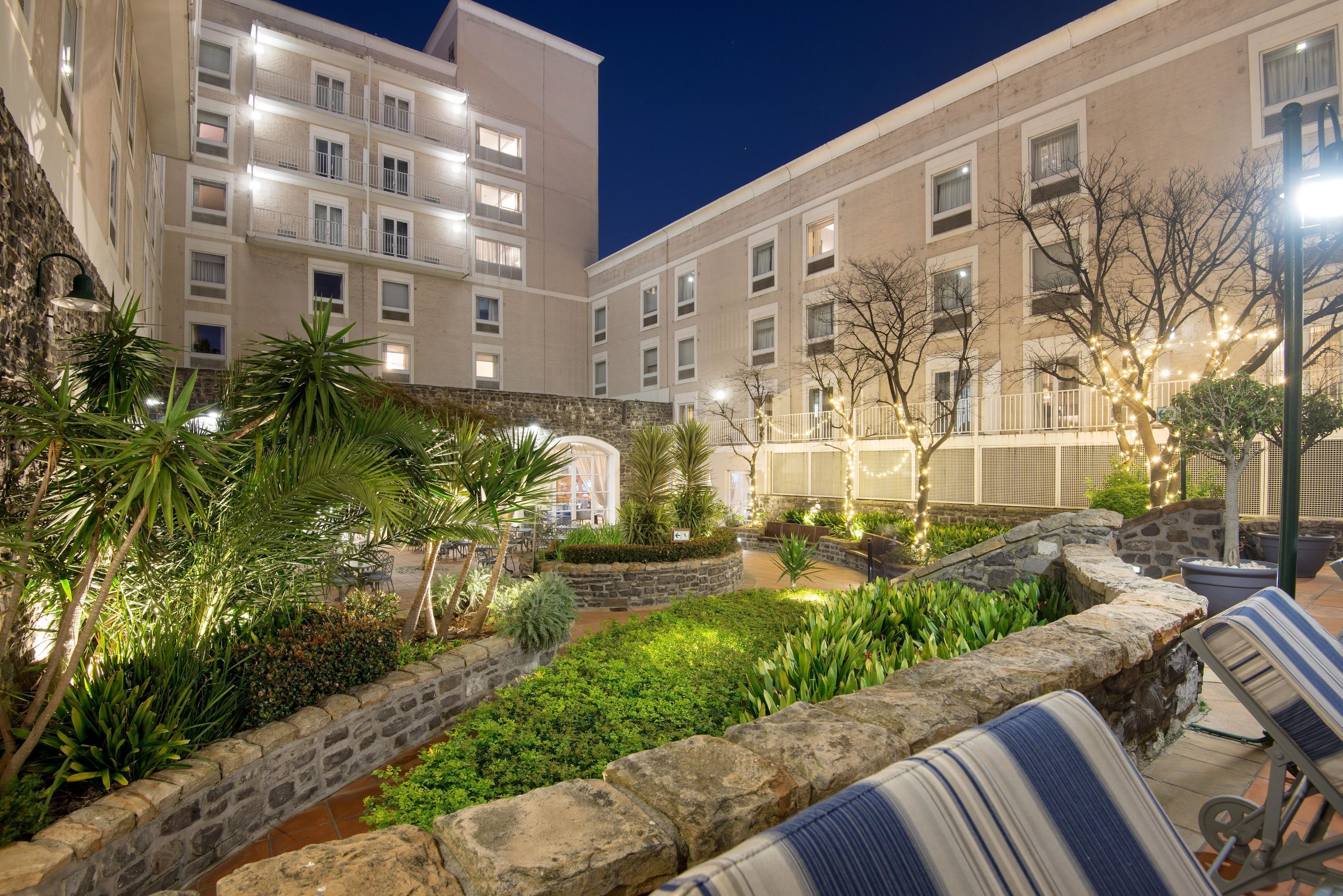 A courtyard with stone walls, green plants, and outdoor seating.