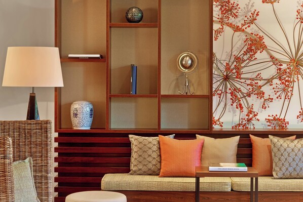 Un salon comprenant un canapé, une lampe et une bibliothèque agrémentée d’objets décoratifs.