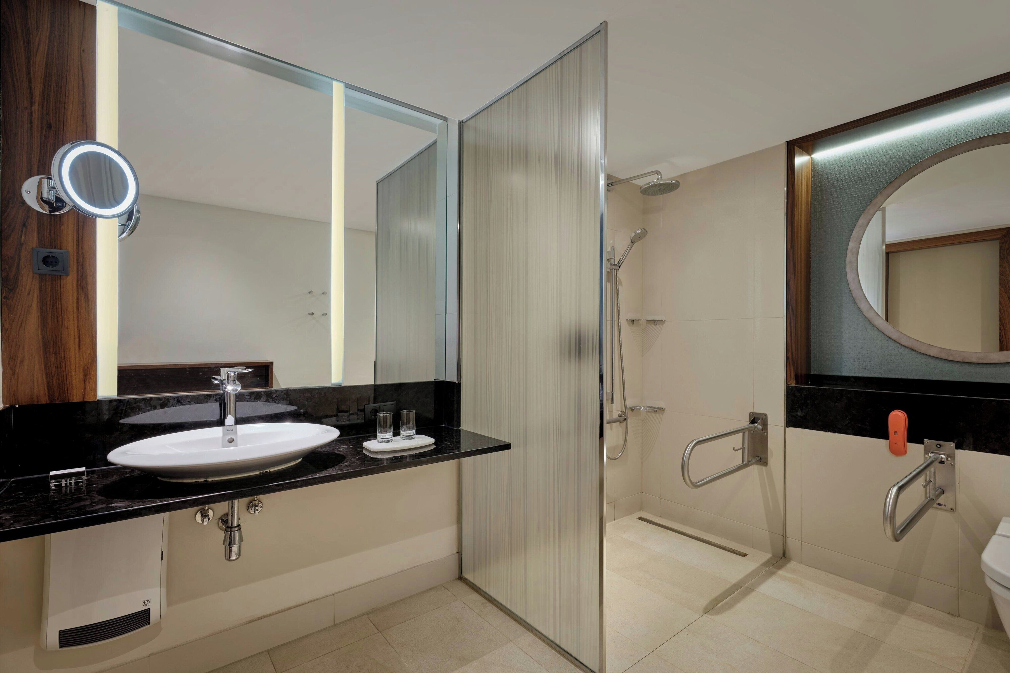 A modern bathroom with a sink, mirror, and shower.