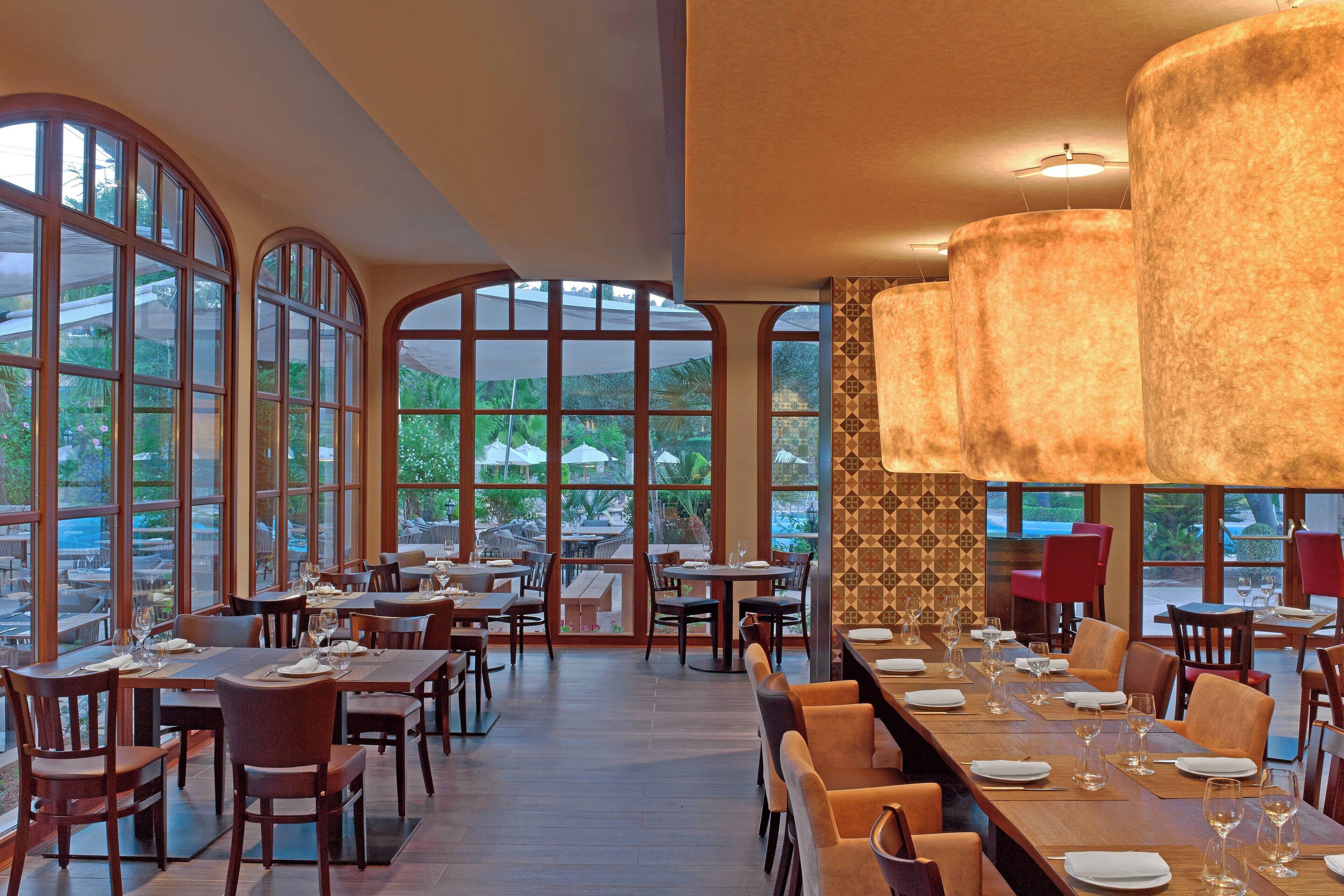 Ein geräumiges Restaurant mit hohen, gewölbten Fenstern, Holztischen und -stühlen.