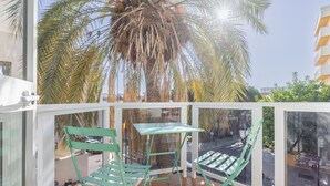 A balcony with a table and chairs, a palm tree, and a view of the street. - Bluesea Miramar Fuengirola (Fuengirola)