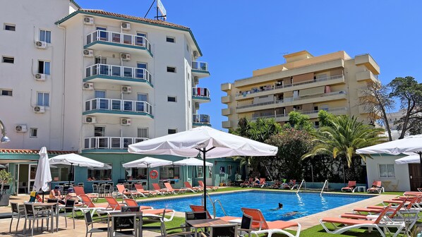 Una piscina al aire libre, sombrillas, tumbonas