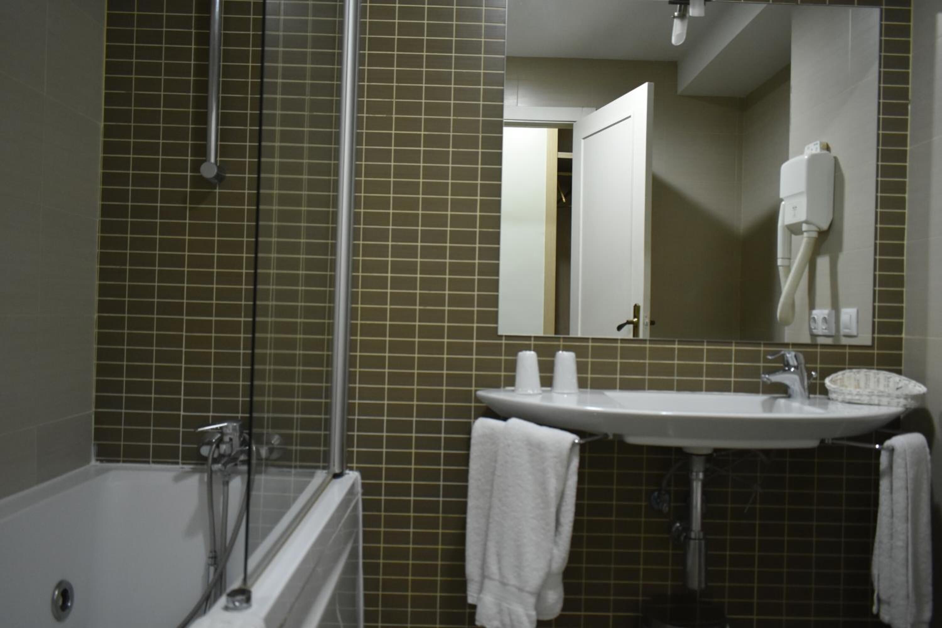 Un baño con bañera, lavamanos y espejo.