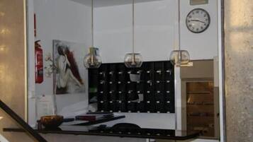 A room with a black and white checkered wall, a clock, and a shelf with various items.