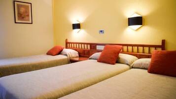 A hotel room with two single beds, each with a wooden headboard, and two wall-mounted night lights.