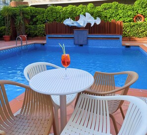 Una piscina al aire libre, sillones reclinables de piscina