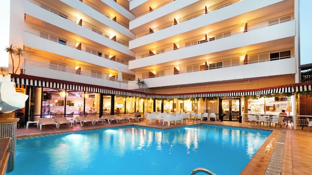 A multi-level hotel with a central swimming pool, outdoor seating areas, and a bar/lounge area.