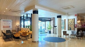 A modern lobby with a polished floor, seating areas, and a large entrance.
