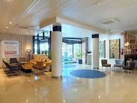 En moderne lobby med slede gulv, siddeområder og en stor indgang.