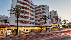 A multi-story hotel with balconies, a ground-level cafe-bar, and a visible liquor store.