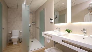 Een moderne badkamer met een glazen douchecabine, toilet, wastafel met spiegel en een handdoekhouder.