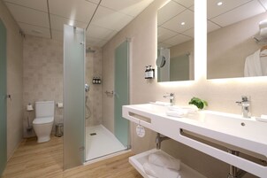 Een moderne badkamer met een glazen douchecabine, toilet, wastafel met spiegel en een handdoekhouder.