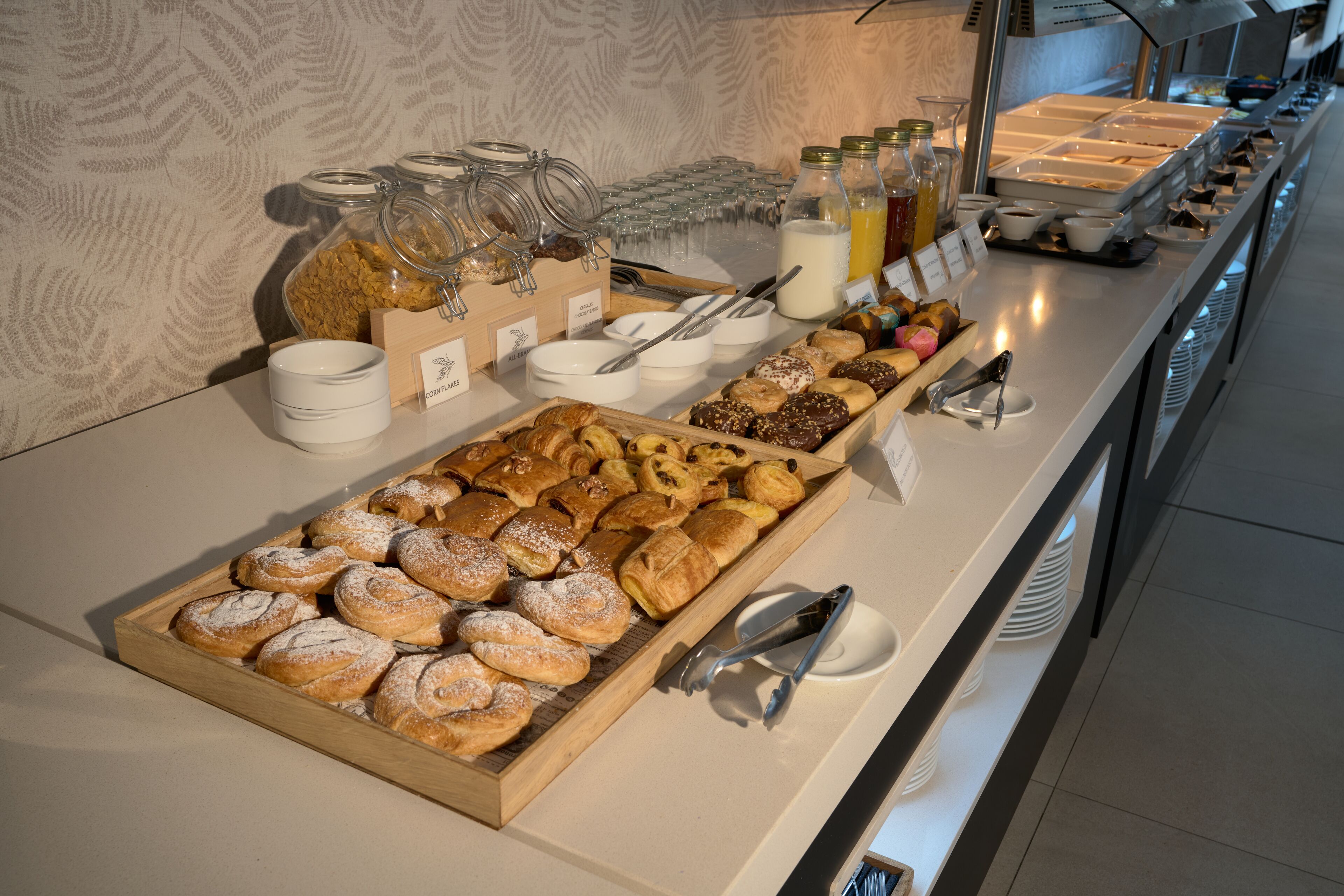 A buffet with various pastries, condiments, and beverages.