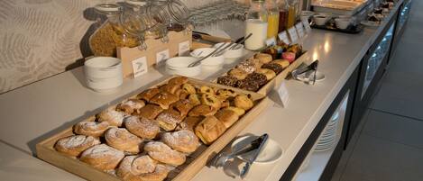 A buffet with various pastries, condiments, and beverages.